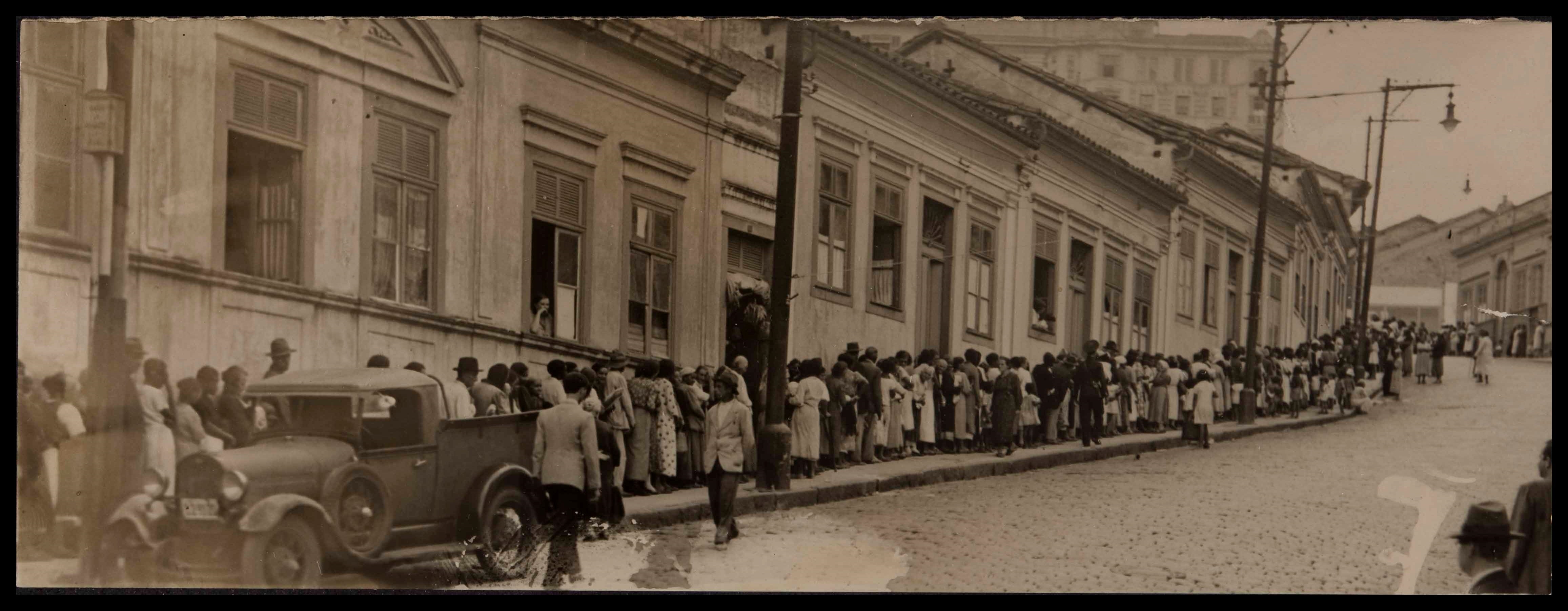 Fila enorme de indigentes esperando cada um o seu quinhão.<br />DN 29/1/1938.