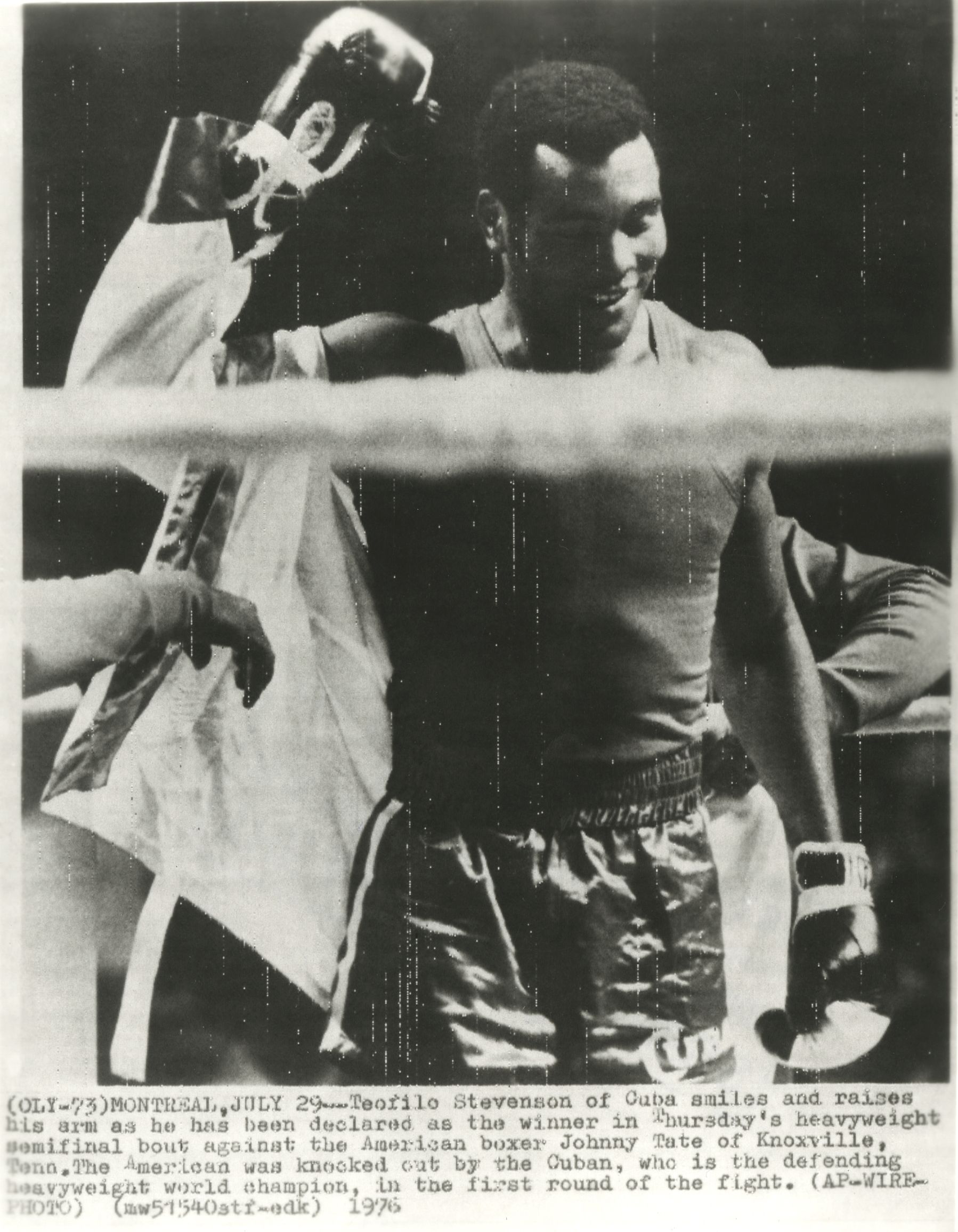 MONTREAL, 29 DE JULHO, 1976 - Teofilo Stevenson, de Cuba, sorri e acena ao ser declarado vencedor na semi-final dos peso-pesados na quinta-feira, vencendo contra o boxeador americano Johny Tate, de Knoxville.(...)