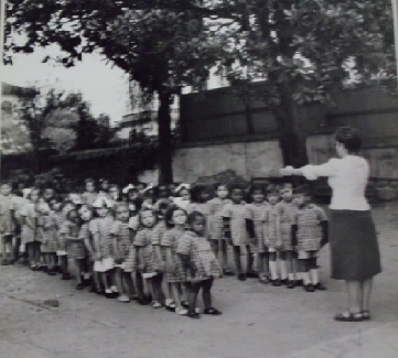 Educadora ordenando as crianças em fila, no Dispensário Central da Cruzada Pró-Infância (Cruzada Pró-Infância, 1935)